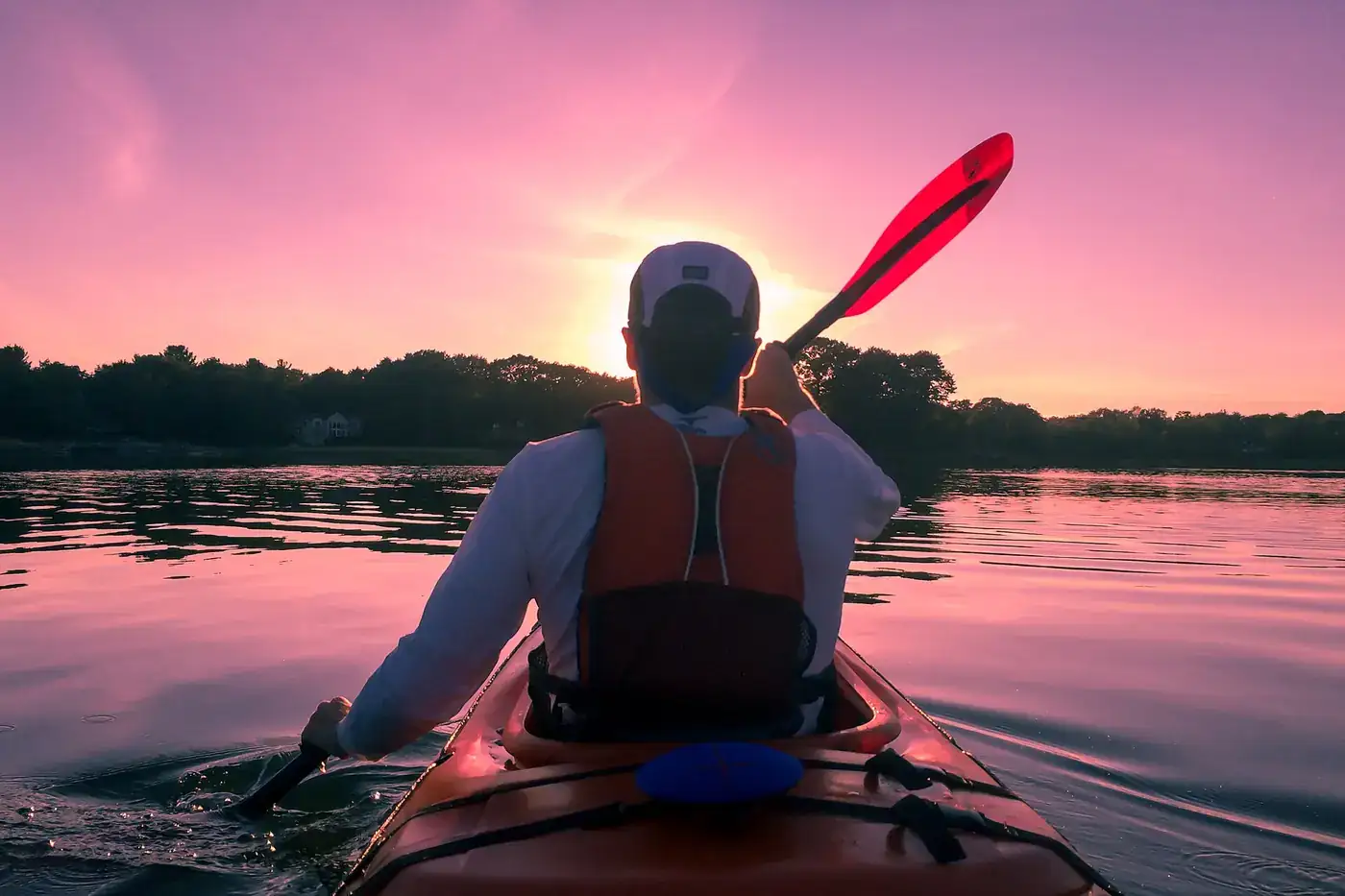 Canoísta a remar numa embarcação estreita sobre água corrente, visto de lado.