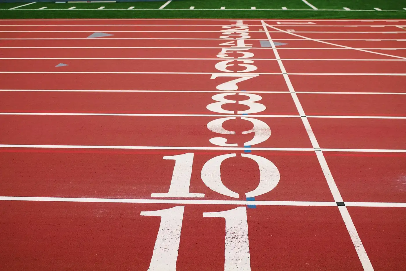 Raias numeradas de uma pista de atletismo vazia, vistas em contrapicado.