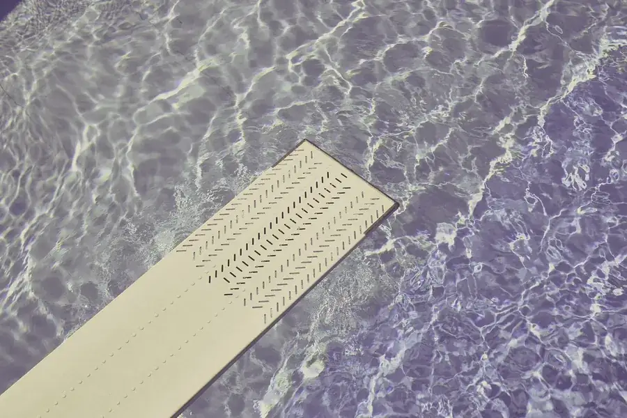 Prancha clara sobre a água transparente de uma piscina, vista de cima.